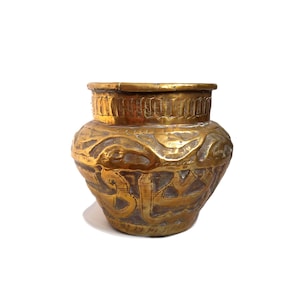Op de afbeelding: Een goudkleurige vaas in antieke stijl met ingewikkelde geëtste patronen. De vaas heeft een brede, afgeronde body en een getextureerde rand. Het oppervlak heeft gedetailleerde gravures, mogelijk Arabisch schrift en geometrische ontwerpen. De vaas staat op een witte achtergrond.