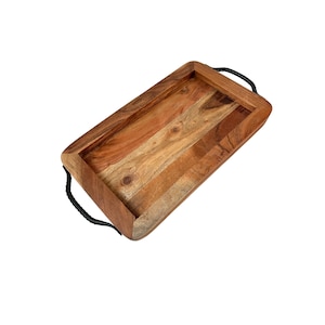 May include: Rectangular wooden serving tray with a natural wood grain finish. The tray has a raised edge and black rope handles on each end. The wood tones range from light to dark brown.