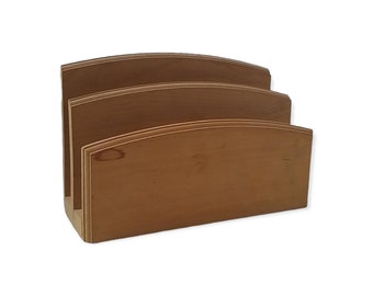 May include: A wooden desk organizer with three sections. The organizer is made of light brown wood and has a curved top design. The sections are separated by vertical dividers, creating slots for storing documents or mail.