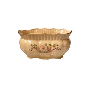 May include: Cream-coloured ceramic planter with a scalloped rim and gold trim. The planter features a floral design with pink and green flowers. The planter has a rounded shape and is suitable for indoor or outdoor use.