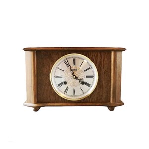 May include: A wooden mantel clock with a light brown finish. The clock face is round with black Roman numerals and hands. The clock has a decorative floral design in the center and is approximately 12 inches wide.