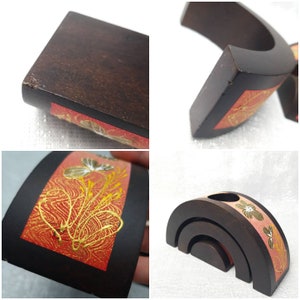 K&ouml;nnte beinhalten: Dunkelbraune Holzdekorst&uuml;cke mit einem roten und goldenen Blumendesign. Das Set beinhaltet ein gebogenes St&uuml;ck und ein stapelbares Bogendesign. Das florale Design weist goldene und wei&szlig;e Akzente auf.