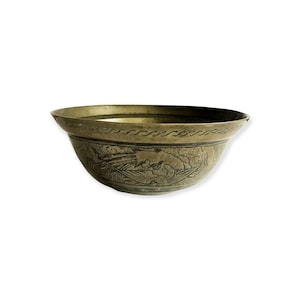 May include: An antique brass bowl with detailed etched patterns. The bowl has a wide rim with a decorative border and relief carvings on the outside. The brass has a warm, aged patina, indicating its age. The bowl is likely for decorative use, with a diameter of approximately 20 cm.