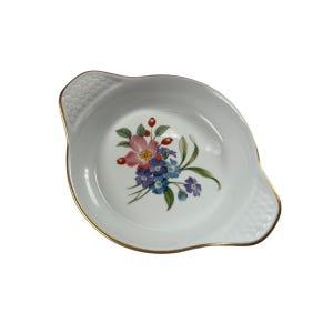 May include: White oval serving dish with a gold rim and handles. The dish features a floral design with pink, blue, and purple flowers. The handles have a textured pattern.