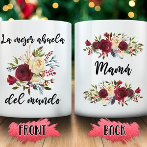 May include: White ceramic mug with floral design and the Spanish text "La mejor abuela del mundo" on the front and "Mam&aacute;" on the back. The floral arrangement includes burgundy, cream, and green elements.