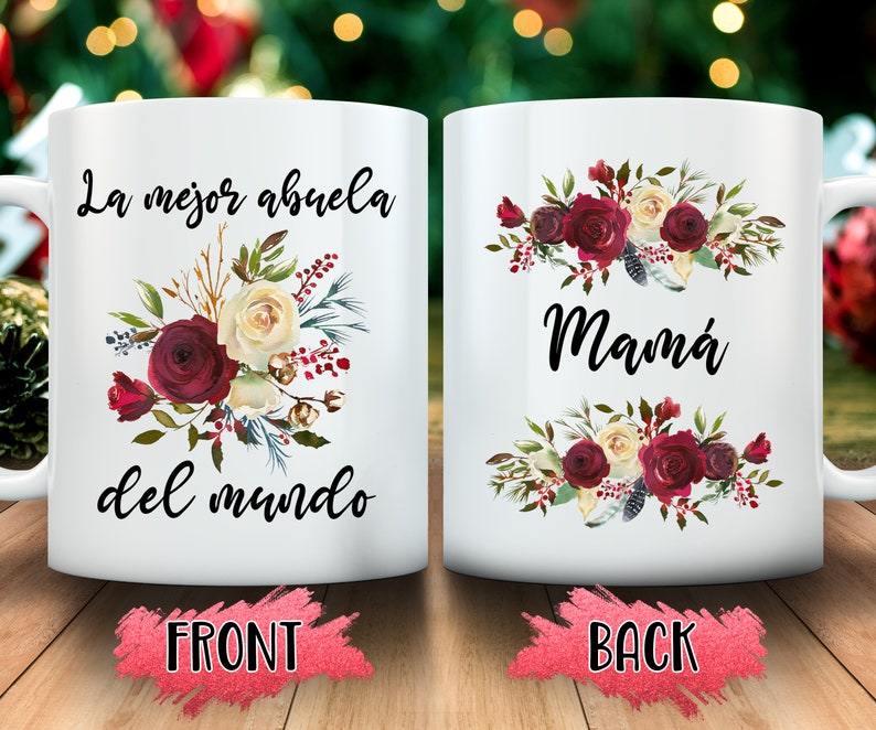 May include: White ceramic mug with floral design and the Spanish text "La mejor abuela del mundo" on the front and "Mam&aacute;" on the back. The floral arrangement includes burgundy, cream, and green elements.