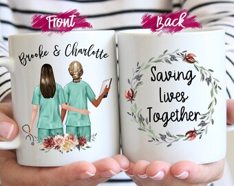 May include: White ceramic mug featuring illustrations of two nurses in teal scrubs, with the names "Brooke & Charlotte" on the front. The back of the mug displays the text "Saving Lives Together" within a floral wreath.