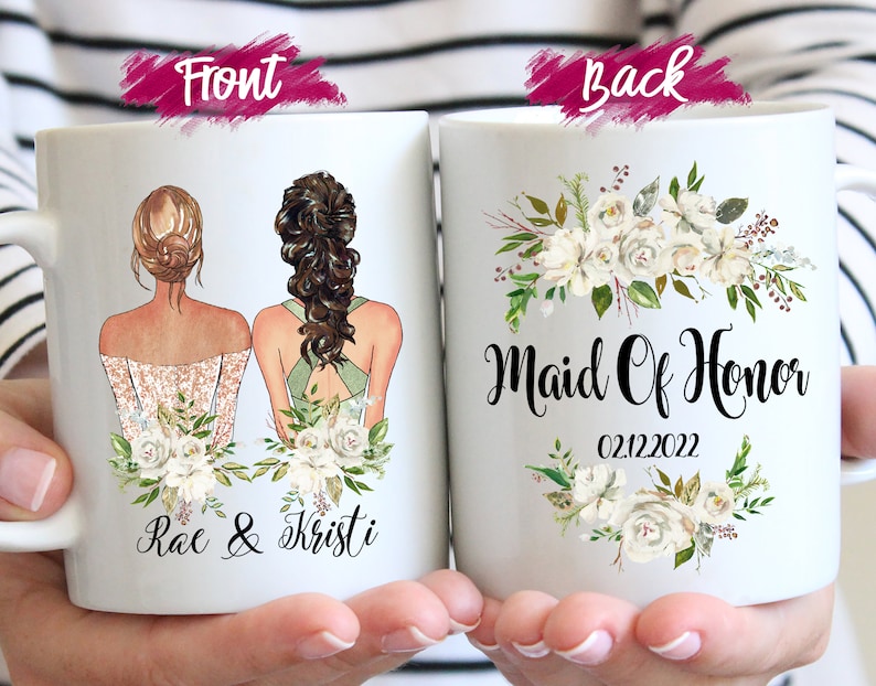 May include: White ceramic mug featuring illustrations of two women in dresses, with floral accents. The front of the mug has the names "Rae & Kristi". The back of the mug says "Maid Of Honor" and the date "02.12.2022".