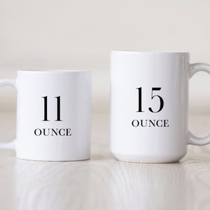 Puede incluir: Dos tazas de cer&aacute;mica blanca con texto negro. La taza m&aacute;s peque&ntilde;a dice "11 onzas" y la taza m&aacute;s grande dice "15 onzas".