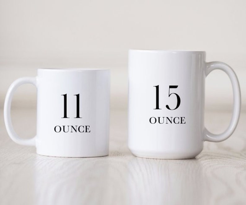Puede incluir: Dos tazas de cer&aacute;mica blanca con texto negro. La taza m&aacute;s peque&ntilde;a dice "11 onzas" y la taza m&aacute;s grande dice "15 onzas".