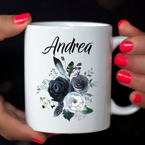 May include: White ceramic mug with a black floral design and the name "Andrea" printed on the front.