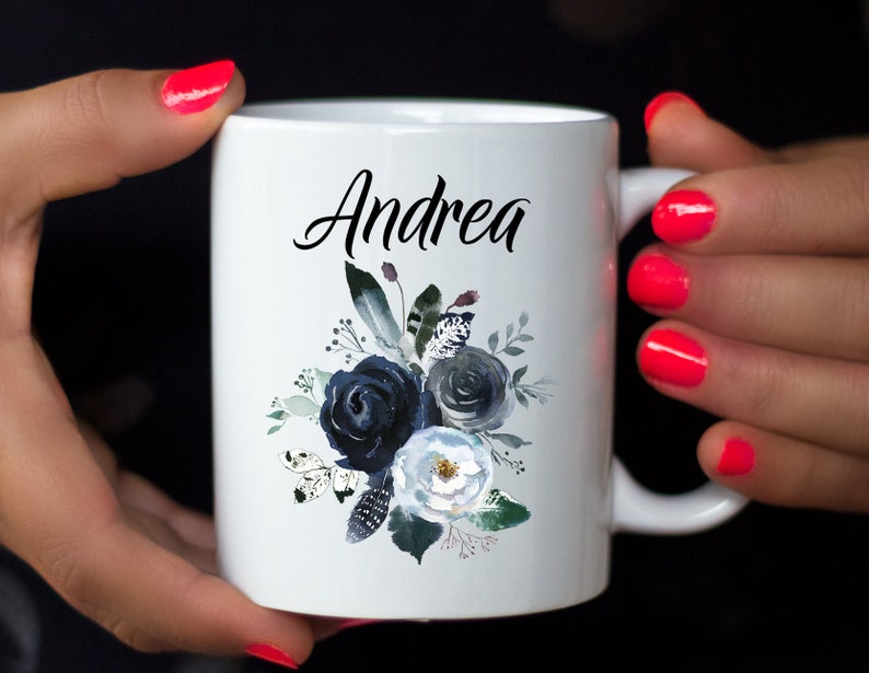 May include: White ceramic mug with a black floral design and the name "Andrea" printed on the front.