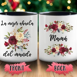 May include: White ceramic mug with a black interior and handle. The front of the mug features the text "La mejor abuela del mundo" with a floral arrangement of burgundy and cream roses. The back of the mug says "Mam&aacute;" with a similar floral design.