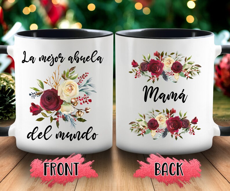 May include: White ceramic mug with a black interior and handle. The front of the mug features the text "La mejor abuela del mundo" with a floral arrangement of burgundy and cream roses. The back of the mug says "Mam&aacute;" with a similar floral design.