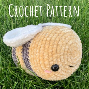 May include: Crochet pattern for a plush bee toy. The bee is made with beige and gray yarn and has white wings. The bee has black eyes and a cute expression.