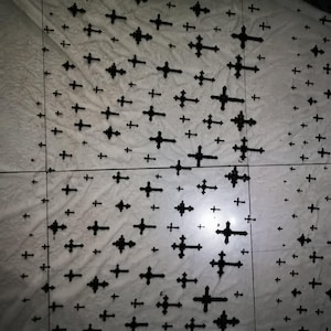 Könnte beinhalten: Ein Muster aus schwarzen Kreuzen unterschiedlicher Größe auf einer weißen, marmorähnlichen Oberfläche. Die Kreuze sind gleichmäßig verteilt und bilden ein sich wiederholendes Motiv. Das Bild hat eine kontrastreiche, monochrome Ästhetik.