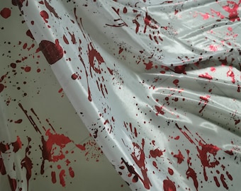 Peut inclure: Un tissu blanc orné d'un motif répétitif d'empreintes de mains et d'éclaboussures rouge métallique. Le matériau présente une surface lisse et réfléchissante avec des plis créant des ombres et des reflets profonds sur le motif graphique.