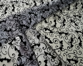 Peut inclure: Tissu noir transparent avec un motif répété de chauves-souris et de volutes. Le tissu est translucide et les chauves-souris sont découpées dans le tissu.