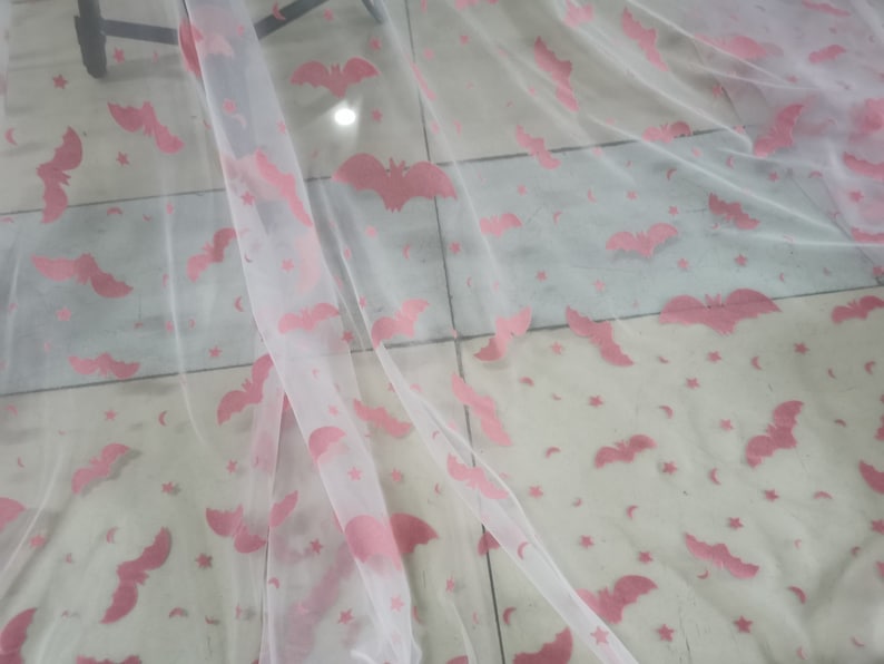 May include: White sheer fabric with a pink bat and star pattern.