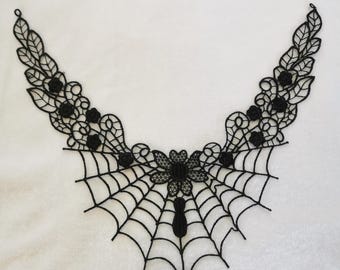 Peut inclure: Col noir en dentelle avec un motif de toile d'araignée. Le col présente des accents floraux et de feuilles, avec de petites roses noires et un motif de toile d'araignée au centre. La dentelle est délicate et complexe, pour un thème gothique ou Halloween.