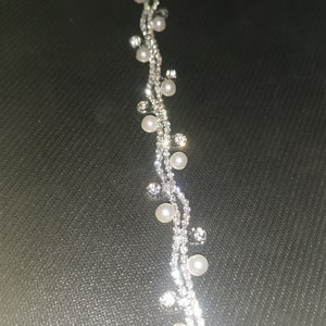 May include: A silver chain bracelet with small white pearls and clear rhinestones.