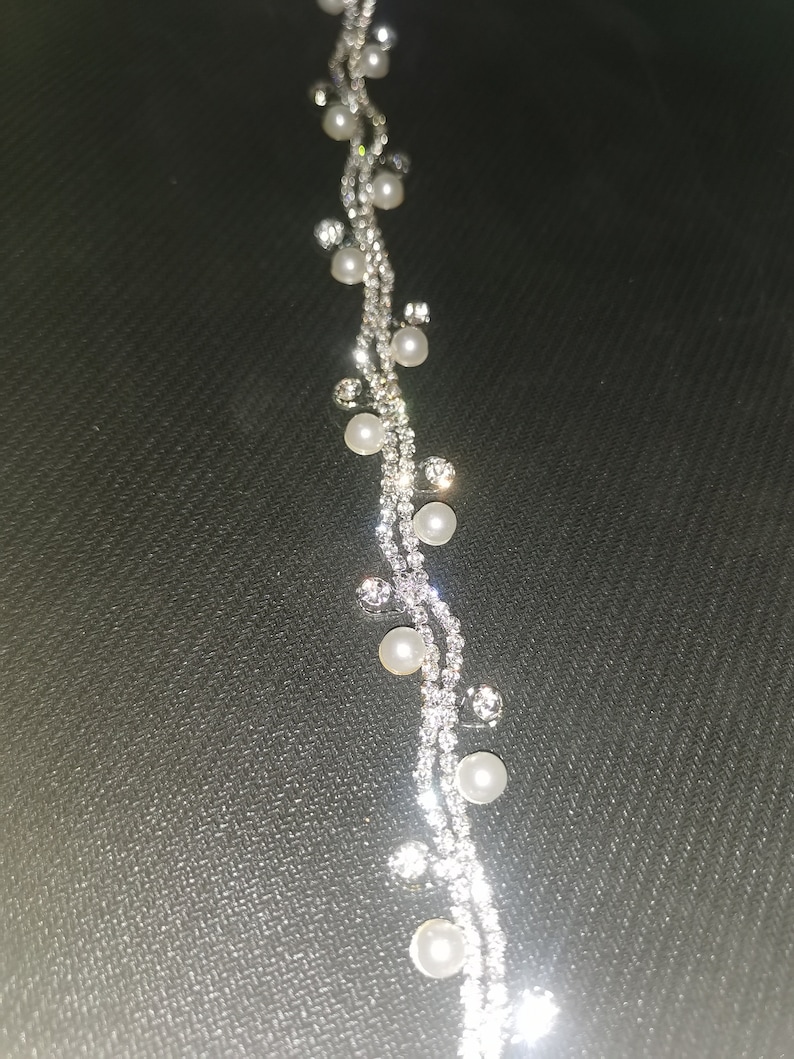 May include: A silver chain bracelet with small white pearls and clear rhinestones.