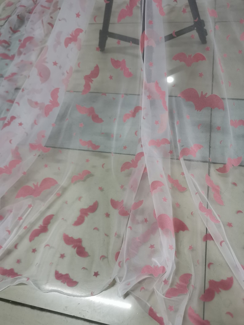 May include: White sheer fabric with a pink bat and star pattern.