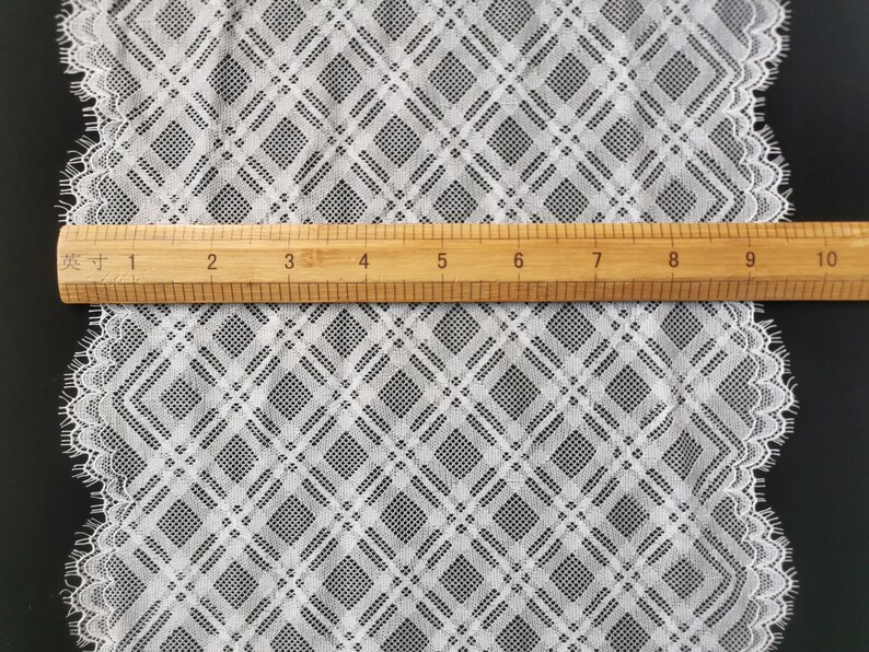 May include: White lace trim with a diamond pattern. The lace is approximately 10 inches wide.
