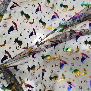 K&ouml;nnte beinhalten: Schwarzer, durchsichtiger Stoff mit einem regenbogenfarbenen, schimmernden Druck von Sternen, Flederm&auml;usen, Katzen und Hexenh&uuml;ten.