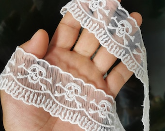 Peut inclure: Dentelle blanche ornée d'un motif répété de têtes de mort et d'os croisés. La dentelle délicate présente un bord festonné. Idéale pour le bricolage et pour ajouter une touche gothique aux projets.