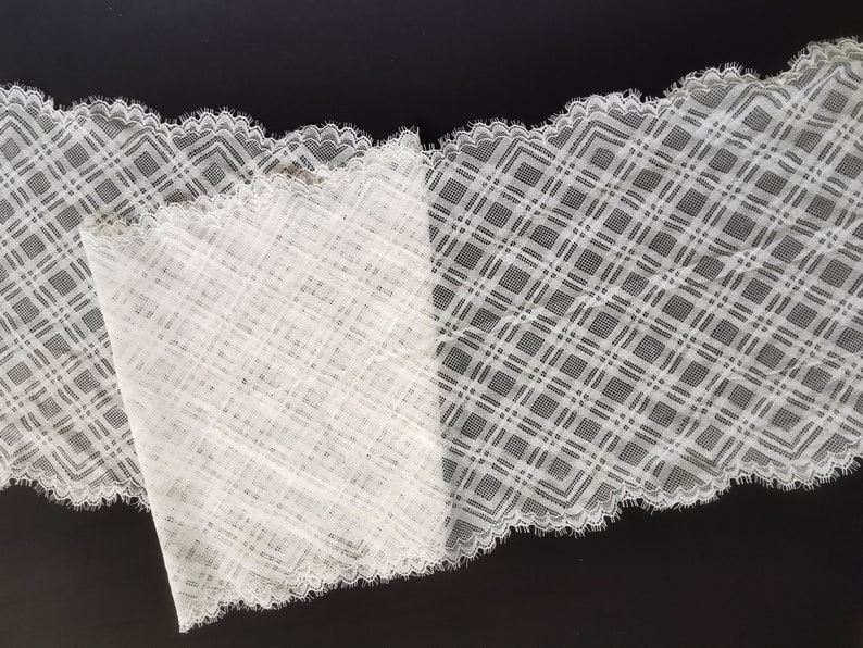 May include: White lace trim with a diamond pattern. The lace has a scalloped edge.