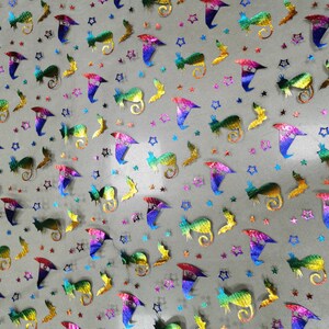 K&ouml;nnte beinhalten: Ein Blatt regenbogenfarbener, irisierender Netzstoff mit einem sich wiederholenden Muster aus Sternen, Flederm&auml;usen und Hexenh&uuml;ten. Der Stoff ist hellgrau und das Muster ist in Regenbogenfarben gehalten.