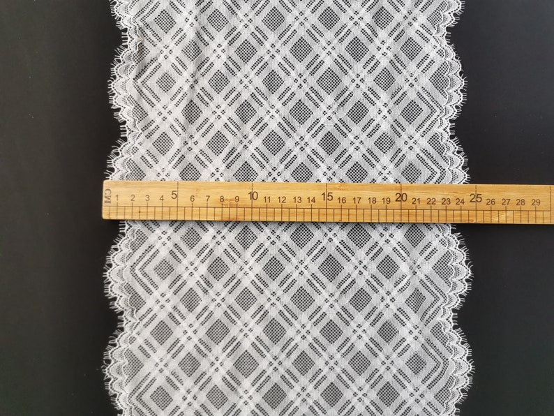 May include: White lace trim with a diamond pattern. The trim is approximately 29 inches long and has a scalloped edge.