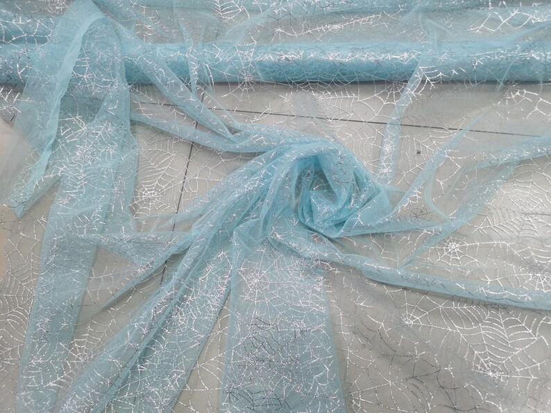 Peut inclure: Tissu de tulle bleu clair avec un motif d'araign&eacute;e en paillettes argent&eacute;es.