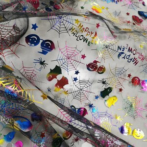 K&ouml;nnte beinhalten: Schwarzer Netzstoff mit einem regenbogenfarbenen, schillernden Druck von Spinnweben, Sternen, Geistern und dem Text "Happy Halloween".