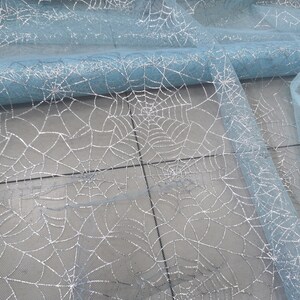 Peut inclure: Tissu de tulle bleu clair avec un motif d'araign&eacute;e en paillettes argent&eacute;es.
