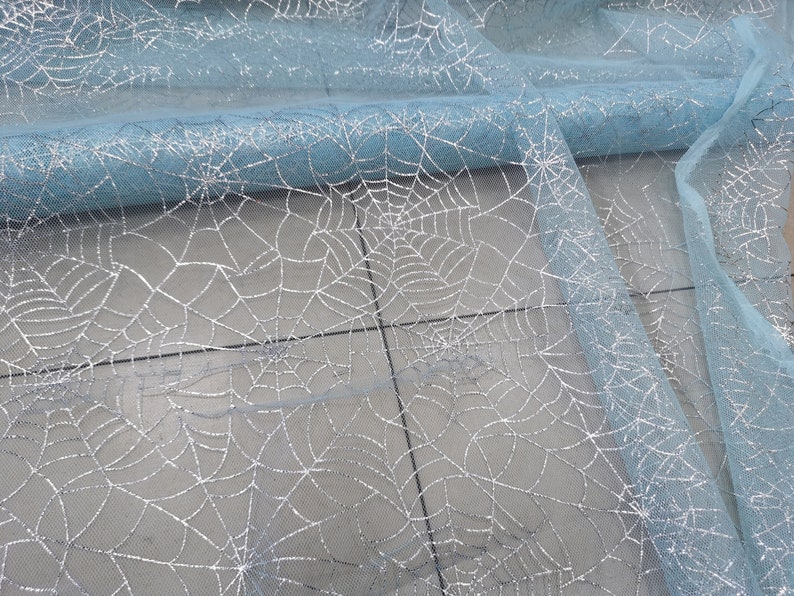 Peut inclure: Tissu de tulle bleu clair avec un motif d'araign&eacute;e en paillettes argent&eacute;es.