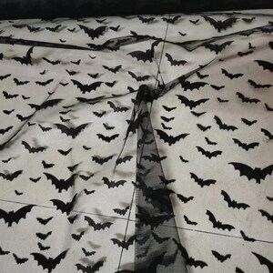 May include: Black sheer fabric with a repeating pattern of bats. The fabric is translucent and the bats are visible against a white background.