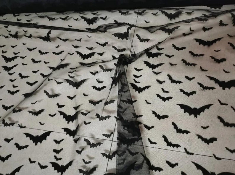 May include: Black sheer fabric with a repeating pattern of bats. The fabric is translucent and the bats are visible against a white background.