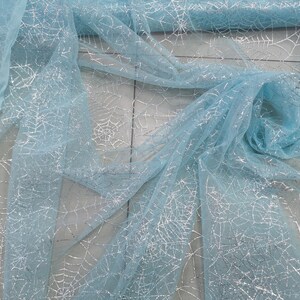 Peut inclure: Tulle bleu clair avec des toiles d'araign&eacute;es en paillettes argent&eacute;es.
