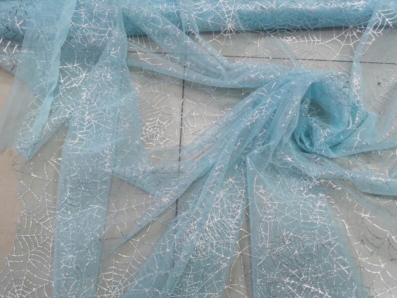 Peut inclure: Tulle bleu clair avec des toiles d'araign&eacute;es en paillettes argent&eacute;es.