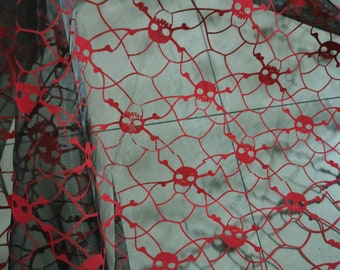 Peut inclure: Tissu en maille noire avec un motif de crâne et d'os croisés rouges. Le tissu est transparent et a une texture délicate.