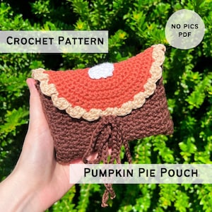 May include: A handmade crochet pouch resembling a pumpkin pie slice. The pouch features a brown base, an orange filling, and a tan crust with a white whipped cream accent. The text "CROCHET PATTERN" and "PUMPKIN PIE POUCH" are displayed.