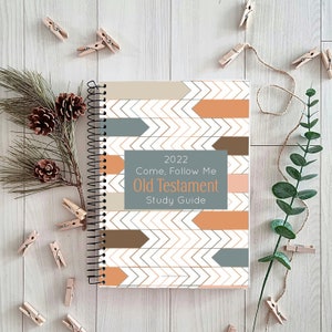 Puede incluir: Una guía de estudio en espiral con un patrón de chevron en tonos marrones, naranjas y grises. El texto de la portada dice "2022 Come, Follow Me Old Testament Study Guide".