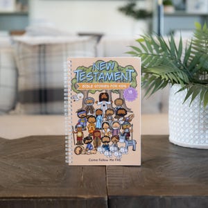 May include: A spiral-bound book titled New Testament Bible Stories for Kids with a light tan cover featuring a colorful cartoon illustration of various figures, trees, a donkey, and sheep, along with the text Come Follow Me FHE at the bottom.