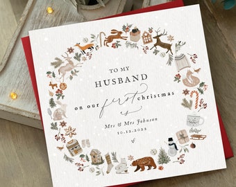May include: A Christmas card with a red border and a white center. The card features a wreath of festive illustrations, including animals, snowflakes, and a cozy sweater. Text reads "To My Husband on our first Christmas" with a date.