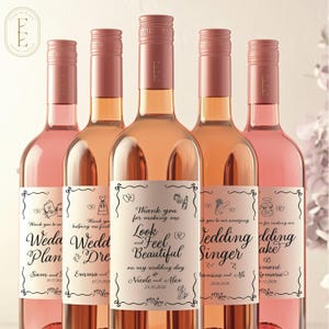 May include: Five glass wine bottles filled with rose-colored liquid, each featuring a custom rectangular label with black text and line art illustrations. The central label reads: Thank you for making me Look and Feel Beautiful on my wedding day.
