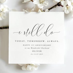 May include: A square white greeting card featuring black text that reads I still do, TODAY. TOMORROW. ALWAYS. HAPPY 1ST ANNIVERSARY to my Wonderful Husband OLIVER Est. 14.07.2025. The card is surrounded by white flower blossoms.