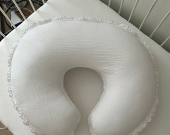 Peut inclure: Oreiller d'allaitement blanc avec une bordure en dentelle crochetée. L'oreiller est en forme de croissant de lune et est conçu pour soutenir un bébé pendant l'allaitement ou le biberon.