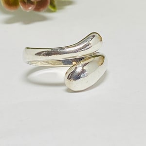 May include: A silver ring with a unique design. The ring is made of two pieces of metal that are twisted together. The ring is simple and elegant.